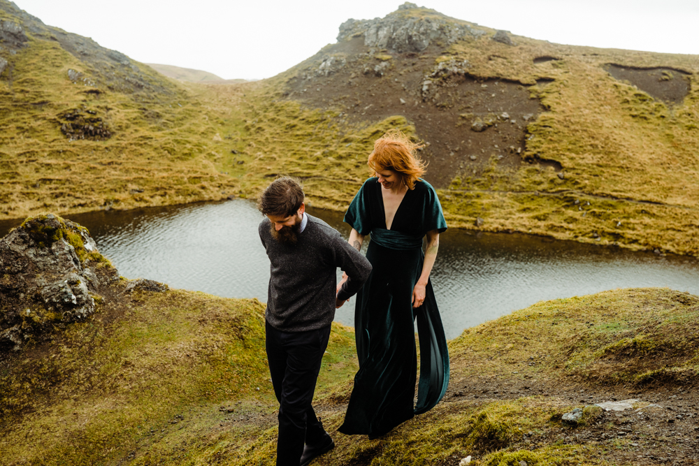 A couple walk together on a grassy hill during their Isle of Skye elopement.