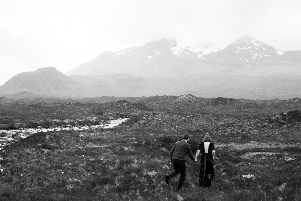 A couple runs in front of mountaints during their Isle of Skye elopement.