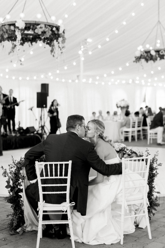 Bride and groom kiss at the sweethearts' table of their wedding reception.
