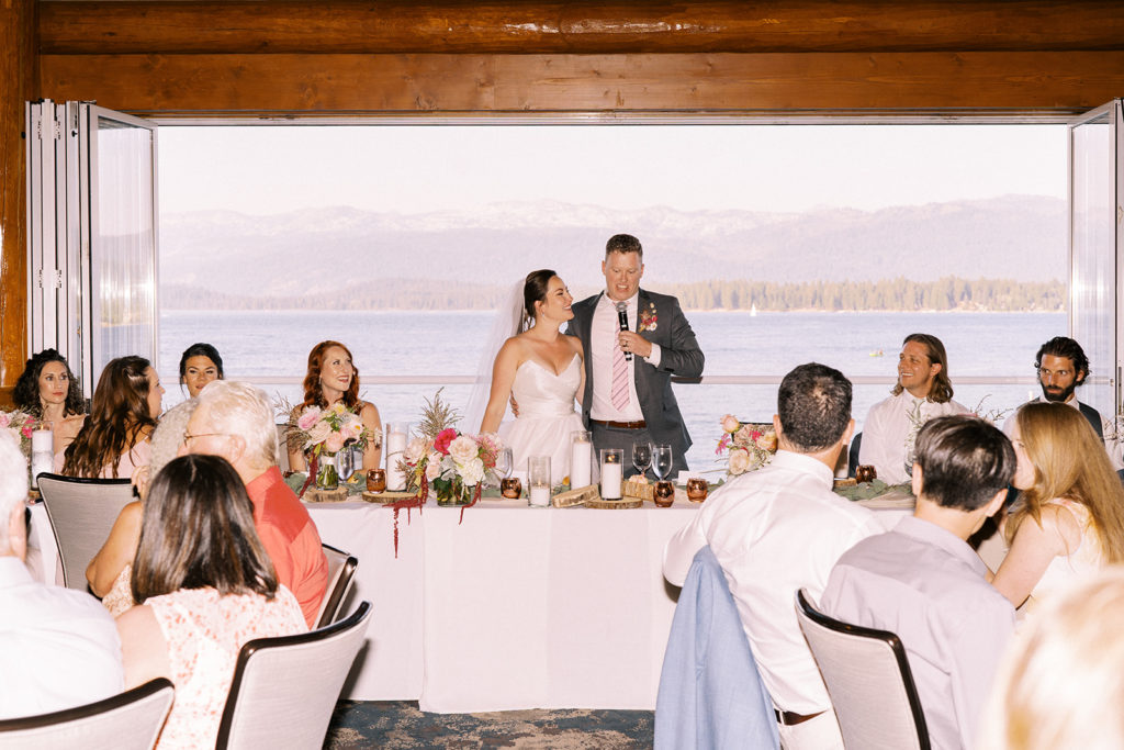Bride and groom speak to guests with mountains in the background at the Shore Lodge McCall wedding.